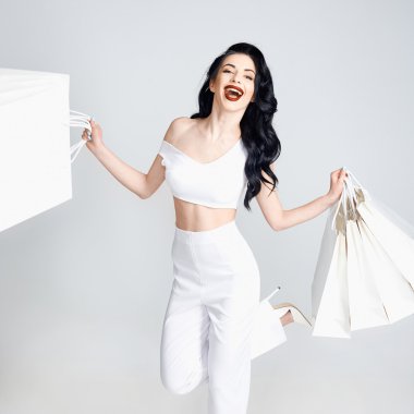 Alışveriş torbaları tutan ve gülümseyen mutlu kadın.