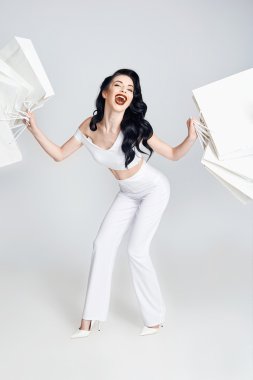 Alışveriş torbaları tutan ve gülümseyen mutlu kadın.