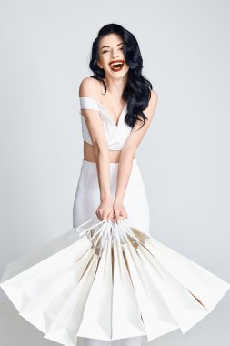 Alışveriş torbaları tutan ve gülümseyen mutlu kadın.