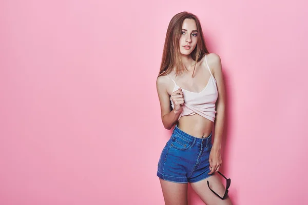 Divertido y colorido. Joven mujer bastante feliz en pantalones cortos posando contra la pared rosa . — Foto de Stock