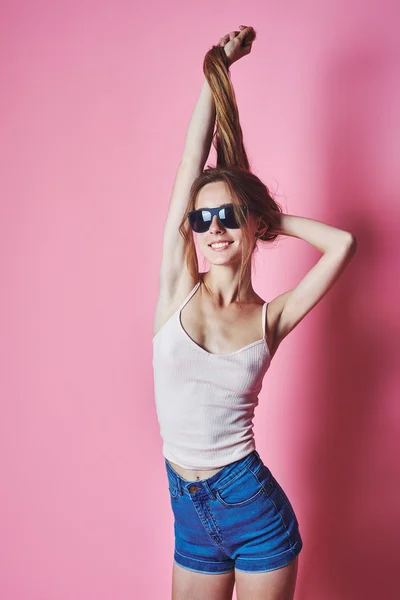 Leuk en kleurrijk. Vrij gelukkig jongedame in korte broek poseren tegen roze muur. — Stockfoto