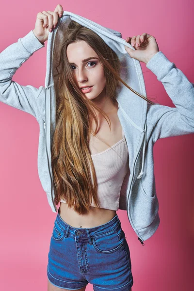 Retrato de chica hipster de moda alegre en casual colorido vivo hipster azul y rosa ropa de verano jeans sobre fondo gris que cubre sus ojos con las manos — Foto de Stock