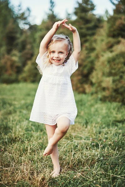 Liten flicka kör på äng med solnedgång — Stockfoto