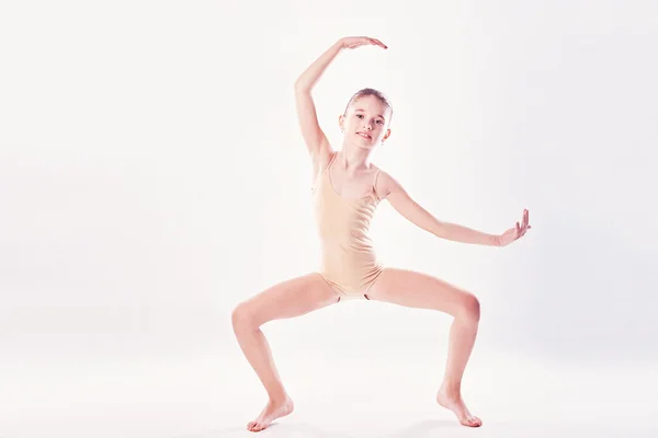 Bambina che fa esercizio di yoga in palestra con grandi finestre sullo sfondo — Foto Stock