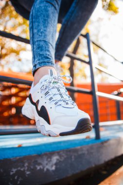 Kotlu bir kızın bacakları ve demir bir çitin üzerinde oturan siyah ayakkabılı beyaz bir kızın bacakları.