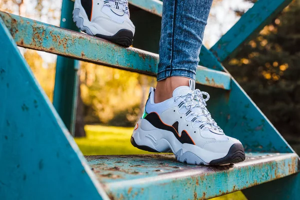 Witte Sneakers Met Zwarte Inzetstukken Vrouwelijke Benen Gekleed Jeans Ijzeren — Stockfoto