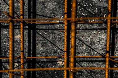 Güçlendirilmiş beton yapımında kullanılan paslı çelik demirin yakın çekimi. Resim, inşaat malzemelerinin yapı ve dokusunu gösterir..