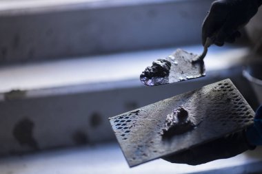 Taze çimento harcı tutan bir inşaat malasının yakın çekimi. Görüntü inşaat malzemeleri ve manuel inşaat çalışmalarına odaklanıyor.