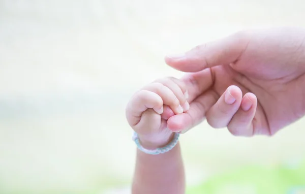 赤ちゃんは、お母さんの指を握り — ストック写真
