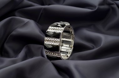 Saten koyu arka plan üzerinde siyah taşlar ile gümüş bilezik