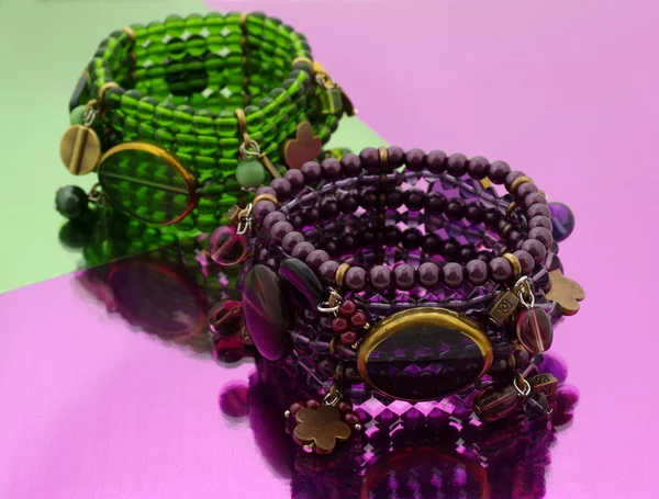 Oriental contas pulseira em verde e roxo espelho de fundo — Fotografia de Stock