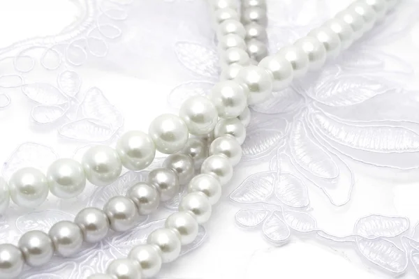 Pearl beads strings on white lace — Stock Photo, Image