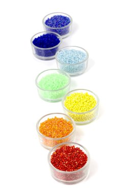 Satır cam beyaz arka plan üzerinde renkli boncuk dolu kase