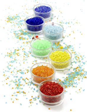 Satır cam beyaz arka plan üzerinde renkli boncuk dolu kase