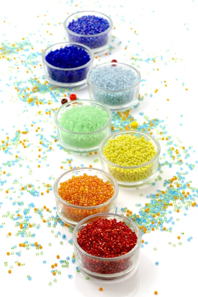 Satır cam beyaz arka plan üzerinde renkli boncuk dolu kase