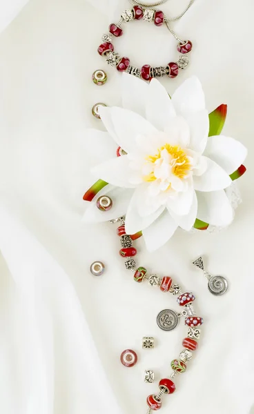 Современные ювелирные изделия с шармом и подвески на белом атласе — стоковое фото