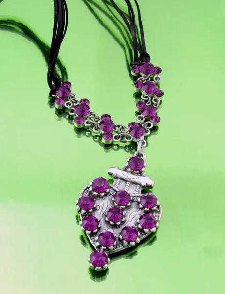 Bijoux mode argent avec strass violets sur fond miroir vert — Photo