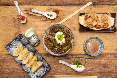 Japon eriştesi ve takoyaki ve gyozas ahşap masada tipik Japon yemeklerinde sunuluyor.