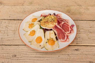 Keçi peynirli salata, salam, marul, armut dilimleri ve bıldırcın yumurtası sarısı.