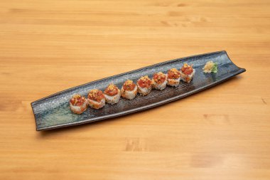 Uramaki rulo baharatlı kırmızı ton balığı ve soğanlı avokado, zencefil ve wasabi uzun siyah tepside.