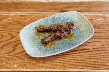 Güzel bir mavi tabak ve meşe ağacından masa üzerinde marine edilmiş sığır eti şişleri.