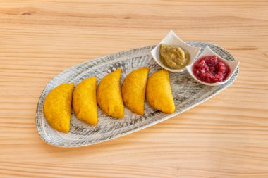 gray tray with delicious Colombian corn dough empanadas served with sauces
