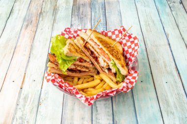 Tavuk, pastırma, domates, marul, jambon, cips ve erimiş peynirli enfes bir kulüp sandviçi.