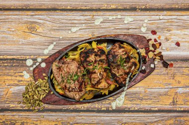 Soğan ve sebzelerden oluşan bir yatakta iyi pişmiş biftek fileto ve üstüne bol miktarda maydanoz.