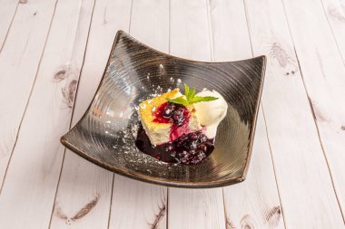 Yaban mersini reçelli cheesecake, nane yaprağı garnitür ve vanilyalı dondurma.