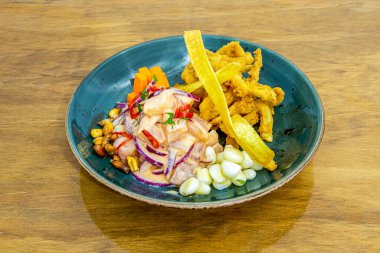 Peru usulü Corvina ceviche, ezilmiş mürekkep balığı ve mısır taneleriyle birlikte güzel bir mavi kase.