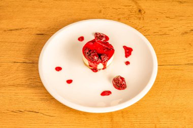 Tarta de queso individual con mucha mermelada de frambuesa ayık plato de porcelana blanca y mesa de madera