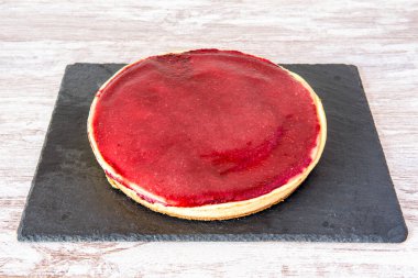 Üzerinde ahududu reçeli olan büyük bir cheesecake.