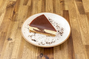 Güzel bir parça endüstriyel cheesecake, üzerinde çikolata ve ahşap masa.