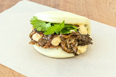 Bao Asya ekmekli sandviç İber domuz yanağıyla yağsız kağıda doldurulmuş.