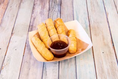 Tray of Venezuelan cheese sticks with sweet apple syrup on wooden table