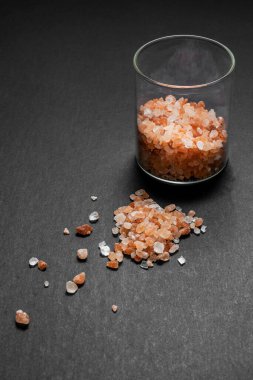 Glass pot with pink himalayan salt stones on plain black background