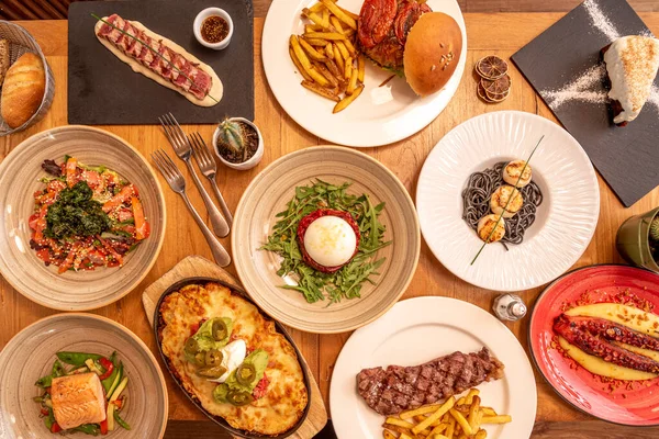 Selection of Italian and Mexican dishes, hamburgers on wooden table