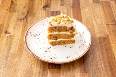 Dondurması ve beyaz tabağında cevizi olan üç katlı havuçlu kek..