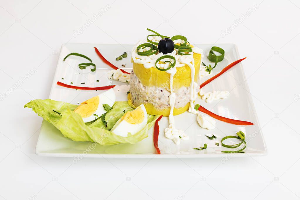 Peruvian Lima cause dish with lots of decoration made with vegetables and herbs on a white plate