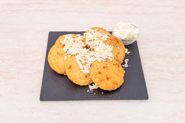 recipe for arepitas with cheese ideal for breakfast on a square plate of black slate on a marble table