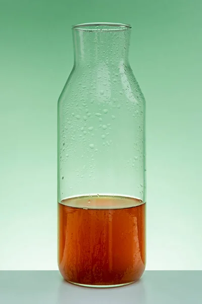 Чай Полуполная Бутылка Стекла Зеленом Столе Подсветка Зеленый Фон — стоковое фото