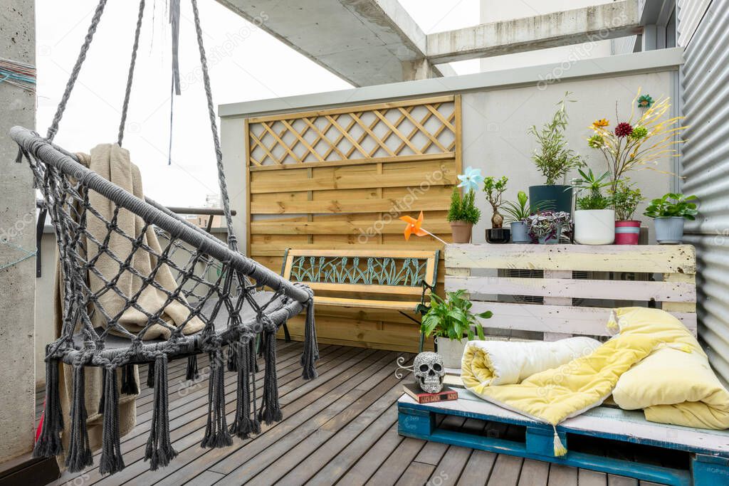 Terrace corner with varied plants, painted pallet sofa, yellow futons and skull in the center