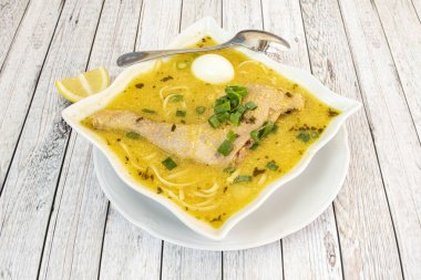Kare şeklinde Peru usulü tavuk çorbası tarifi erişte, soğan ve kaynamış yumurta hafif ahşap masada.