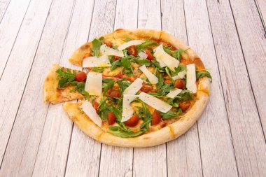 İtalyan pizzası roka, vişneli domates, parmesan peyniri, domates ve ahşap tahtada mozzarella peyniri.