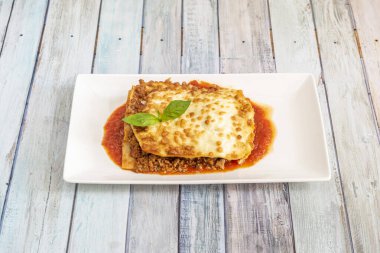 Lezzetli bir porsiyon domates soslu kıymalı lazanya ve beşamel peynirli makarna örtüsü.