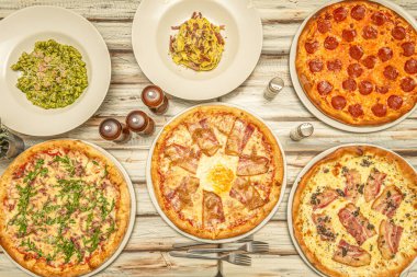 İtalyan makarna yemekleri ve tipik İtalyan pizzaları, guanciale ve ahşap masada pepperoni.