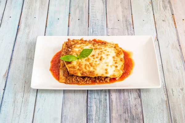 Lezzetli bir porsiyon domates soslu kıymalı lazanya ve beşamel peynirli makarna örtüsü.