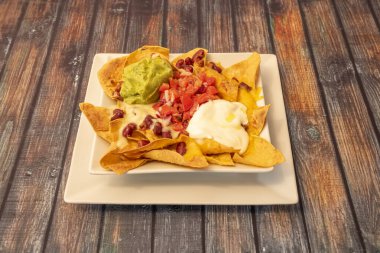 Guacamole soslu nachos, pico de gallo, kırmızı fasulye ve iki çeşit peynir.