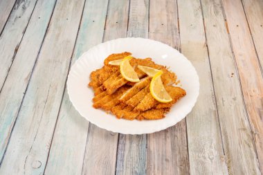 Beyaz tabakta limon dilimleri olan kızarmış tavuk filetoları