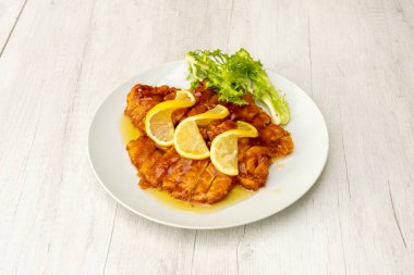 Çin usulü limon soslu tavuk göğsü filetosu ve beyaz tabakta dilimler.